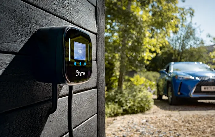 Ohme ePod EV charger installed outside a UK home on a timber wall with EV in background